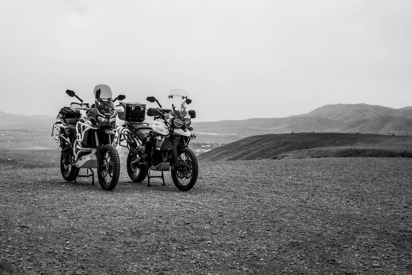 Two adventure motorcycles parked on a dirt road