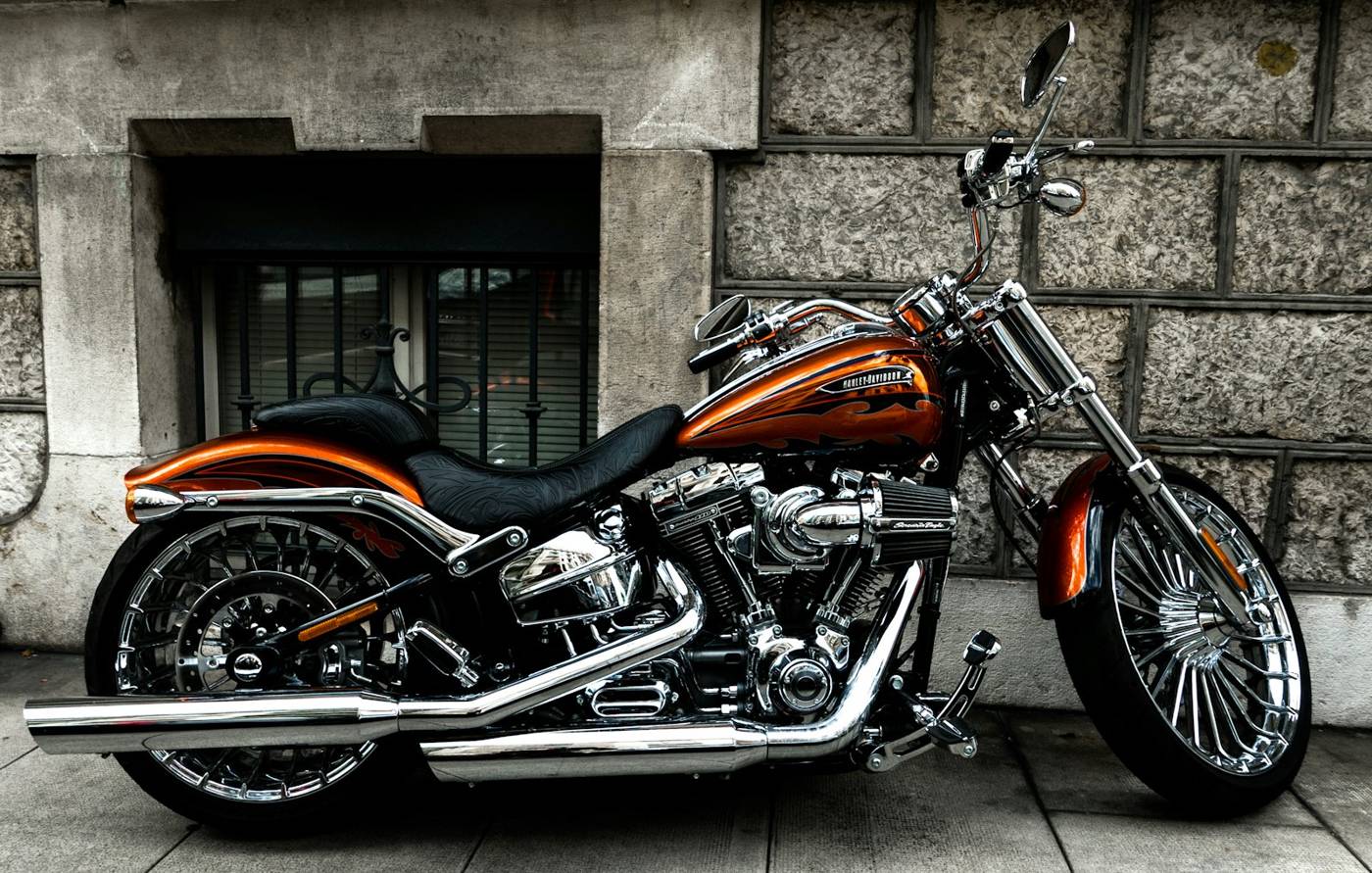 Cruiser motorcycle with a low seat parked beside a stone wall