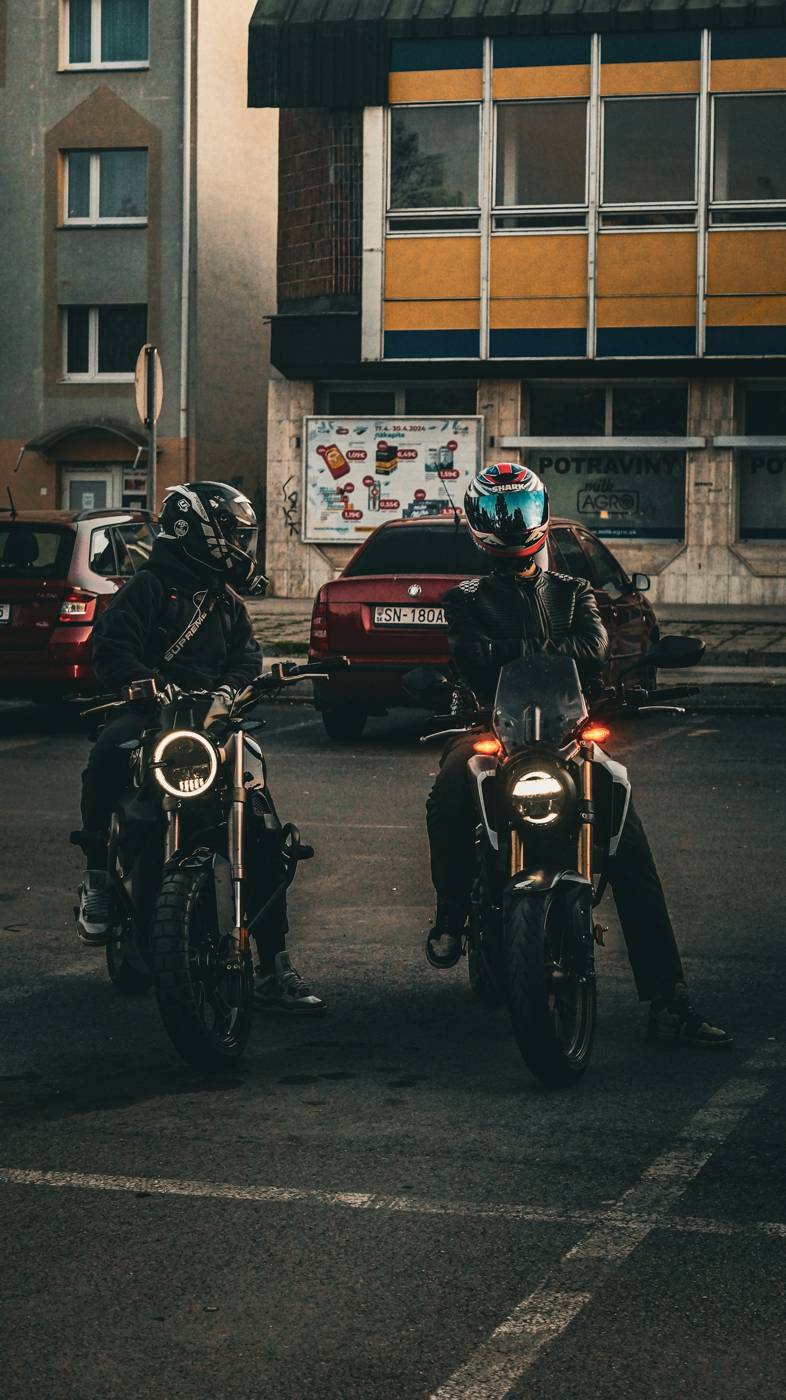 Riding friends Two motorcycle riders sitting on their parked bikes talking