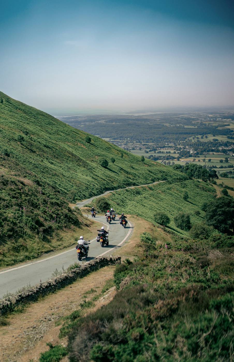 Group ride Group of motorcyclists riding a curving hillside road