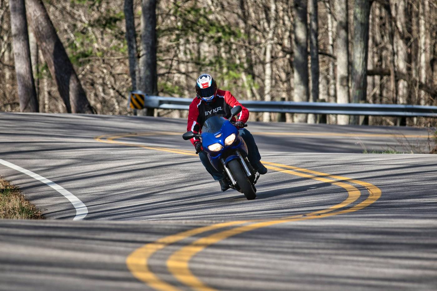 Leaning into a curve Motorcyclist leaning through a curve on a tree-lined road